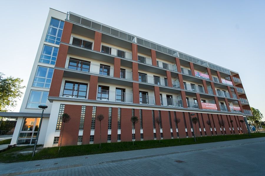 Nowe Miasto Pruszków, elewacja z cegłą klinkierową i przeszklonymi balkonami o zachodzie słońca