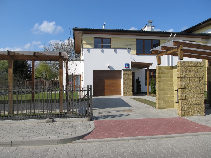 Wiśniowy Sad, wjazd do domu z drewnianą bramą garażową i murowanym ogrodzeniem